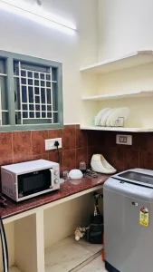 Ramalinganagar Home First Floor – Kitchen with microwave oven and washing machine